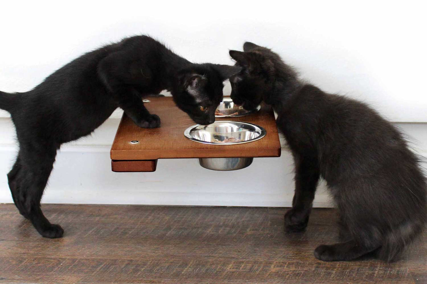 Wall mounted bamboo cat feeding shelf with two food dishes and an escape hatch opening above