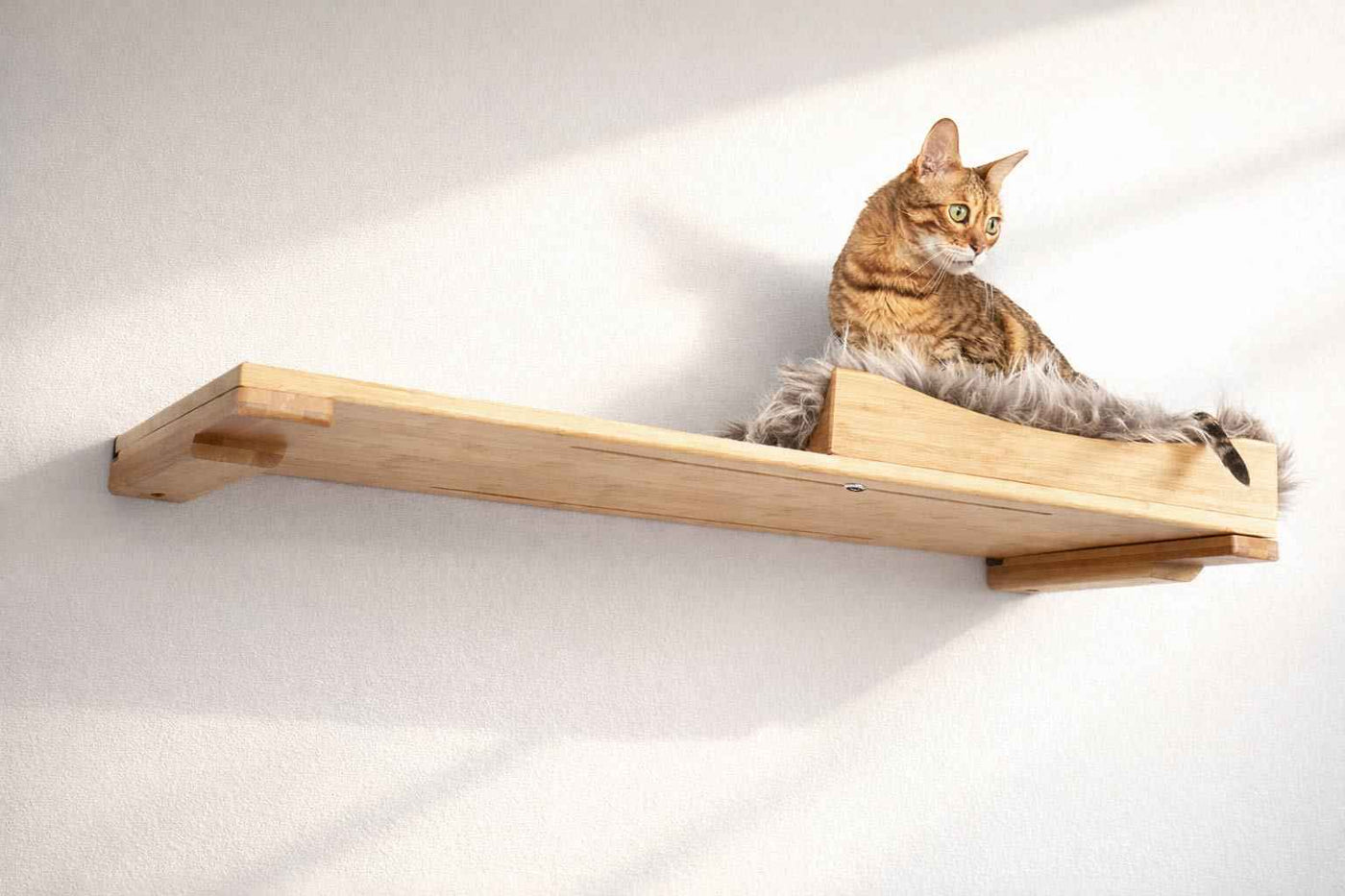 Wall-mounted bamboo cat bed with a curved front ledge and faux fur pad