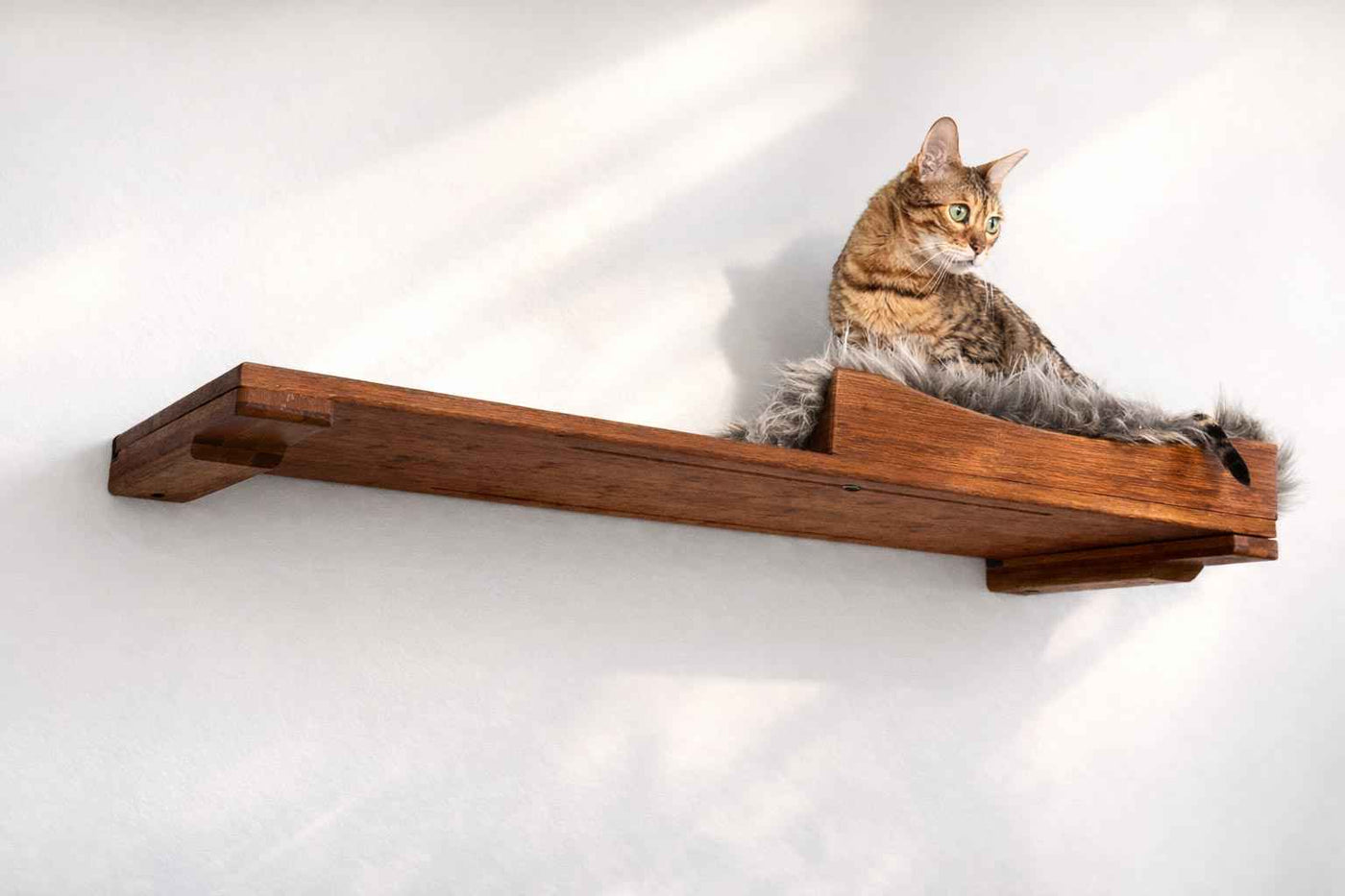 Wall-mounted bamboo cat bed with a curved front ledge and faux fur pad